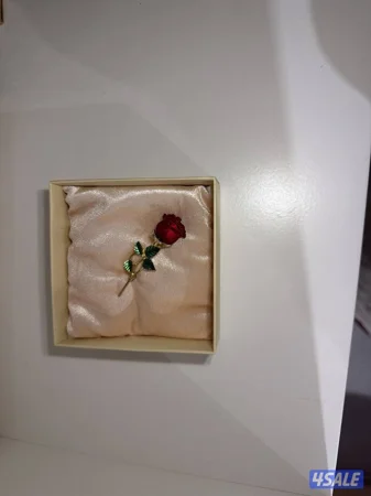 Rose shaped brooch (pin) with a gold-tone stem,green leaves,and a rose